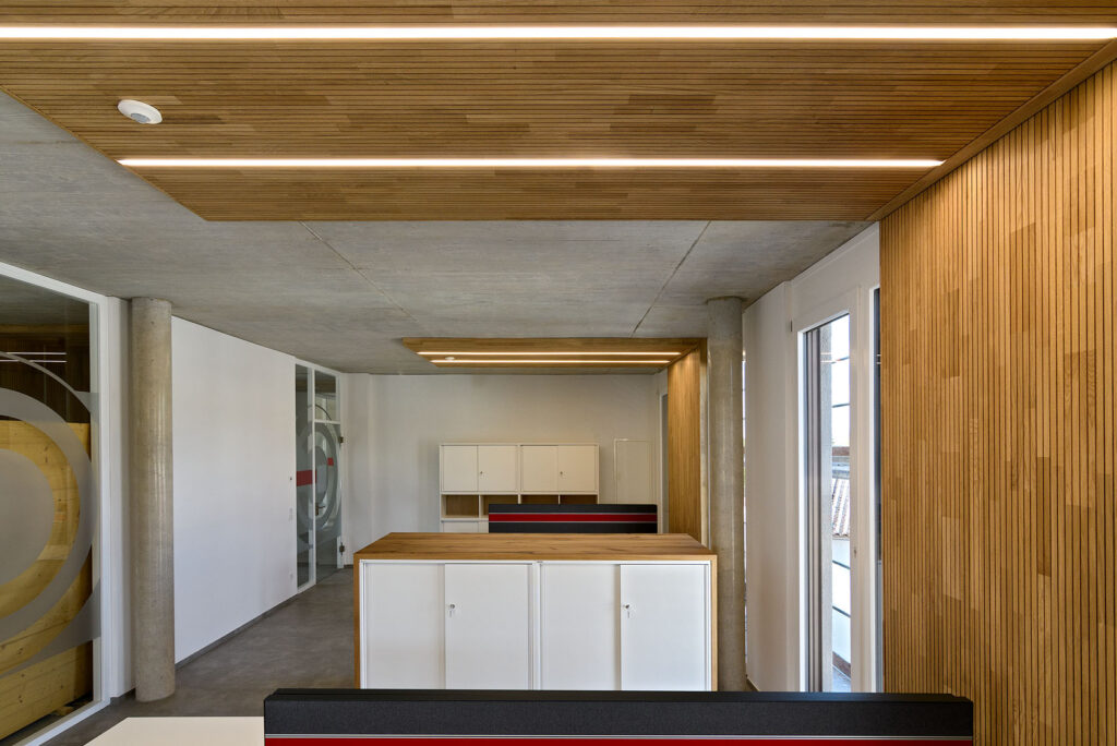 Büro mit Holzplatten an Wand und mit Beleuchtung an der Decke